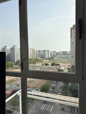Blick aus einem Fenster mit mehreren Fensterscheiben auf eine Stadtlandschaft mit Hochhäusern, einer Straße mit Fahrzeugen und einer Fußgängerampel.