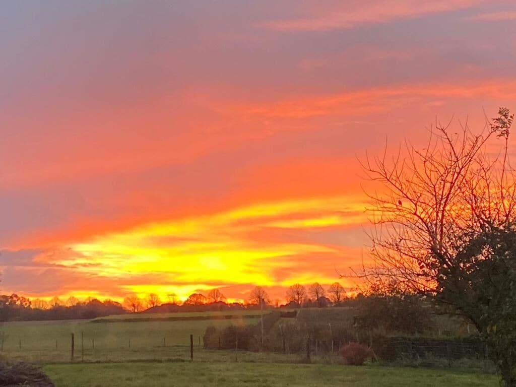 Een landelijk landschap met een zonsondergang, open velden en een omheining.