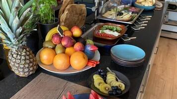 A kitchen counter with various fruits and vegetables, including apples, oranges, and watermelon.