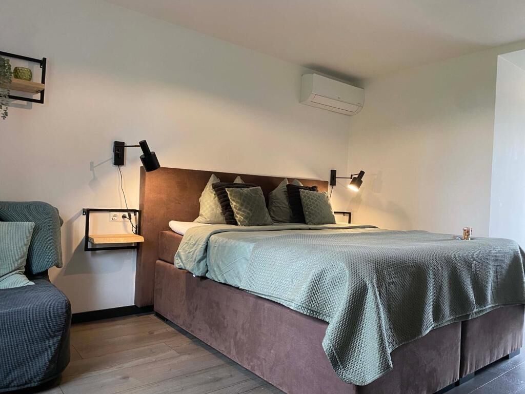 Een slaapkamer met een bed, nachtkastjes en een wandairconditioner.