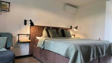 Een slaapkamer met een bed, nachtkastjes en een wandairconditioner.