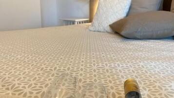 Una cama con una colcha estampada, dos copas de vino vacías y una botella de vino sobre la cama.