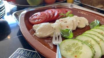 Une assiette de salade caprese, composée de tomates, de mozzarella et de basilic, avec une étiquette noire indiquant « ENSALADA CAPPESE ».