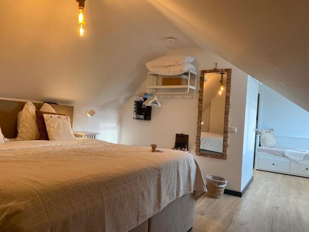 Une chambre avec un grand lit, une étagère suspendue, un miroir et une vue sur un balcon.