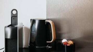 A coffee maker, a mug, and a container with coffee pods on a countertop.