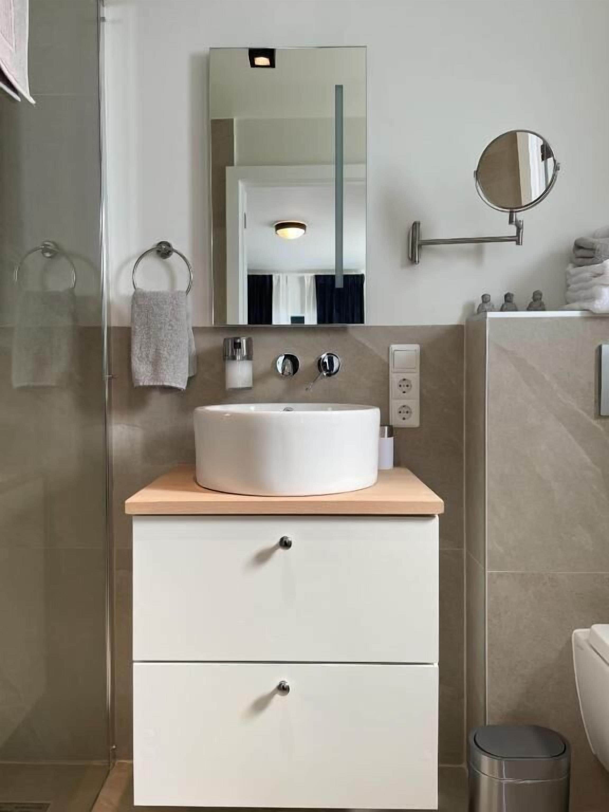 A modern bathroom with a white sink, a mirror, and a towel rack.