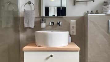 A modern bathroom with a white sink, a mirror, and a towel rack.