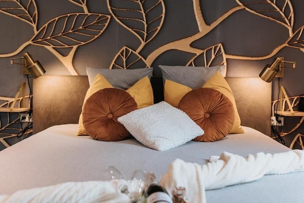 Una habitación de hotel con una cama, paneles decorativos en la pared y dos lámparas de noche.