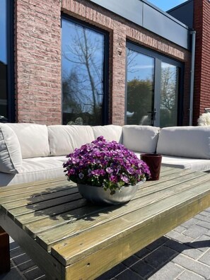 Ein Sitzbereich im Freien mit einem Holztisch und einem Blumentopf.
