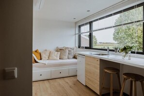 Eine moderne Küche mit eingebautem Geschirrspüler, einem Fenster mit Jalousien und Blick ins Freie.