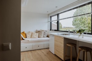 Una cocina moderna con lavavajillas incorporado, una ventana con persianas y vistas al exterior.