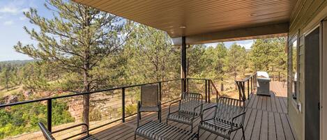 A covered outdoor deck with metal chairs and a grill.
