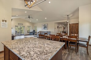 A spacious kitchen with a large granite island, wooden dining table, and chairs. - One of a kind view in the south-central Black Hills - Emerald Canyon (Hermosa)