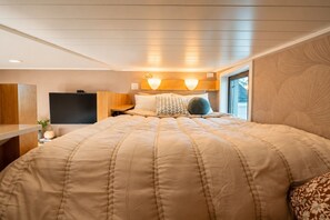 Quarto com cama grande, televisão e janela.