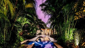 A swimming pool surrounded by lush greenery and a building in the background. - Three bedroom  in Costa Rica, Playa Langosta (Tamarindo)