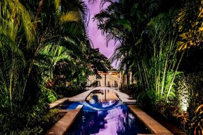 A swimming pool surrounded by lush greenery and a building in the background. - Three bedroom  in Costa Rica, Playa Langosta (Tamarindo)