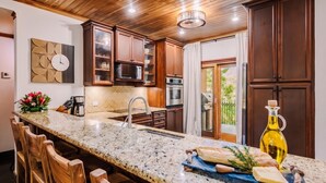 A kitchen with wooden cabinets, a granite countertop, and a built-in oven. - Three bedroom  in Costa Rica, Playa Langosta (Tamarindo)