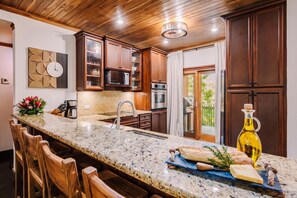 A kitchen with wooden cabinets, a granite countertop, and a built-in oven. - Three bedroom  in Costa Rica, Playa Langosta (Tamarindo)