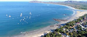 Eine Luftaufnahme einer Küstenregion mit Strand, Booten und einem Wohngebiet mit Häusern.