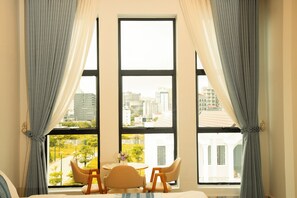 A hotel room with a large window, a bed, two chairs, and a small table with a vase of flowers. - Starlight Beach Hotel (Sihanoukville)