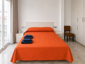 Een hotelkamer met een bed, nachtkastje, stoel en kledingkast.