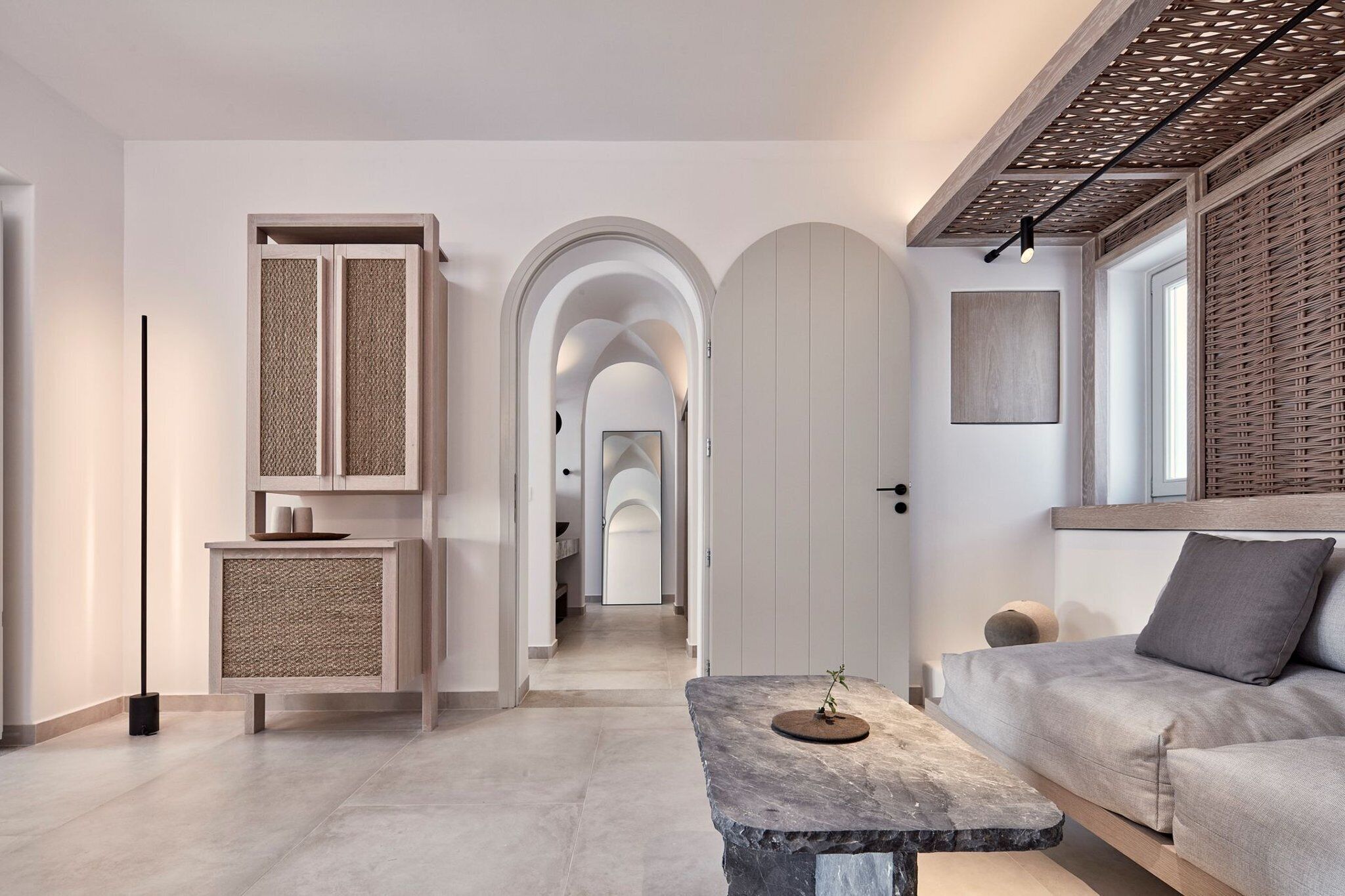 Un interno moderno con un divano, un tavolo in pietra e un corridoio che conduce a una porta ad arco.