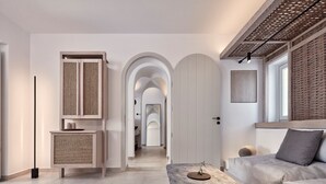 A modern interior with a sofa, a stone table, and a hallway leading to an arched doorway. - Villa Lythion, Divine Sea Views, Private Pool, Furnished Terrace, Sanrotini (Oia, Santorini)