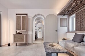 Ein modernes Interieur mit einer Couch, einem Steintisch und einem Flur, der zu einem Rundbogen führt.