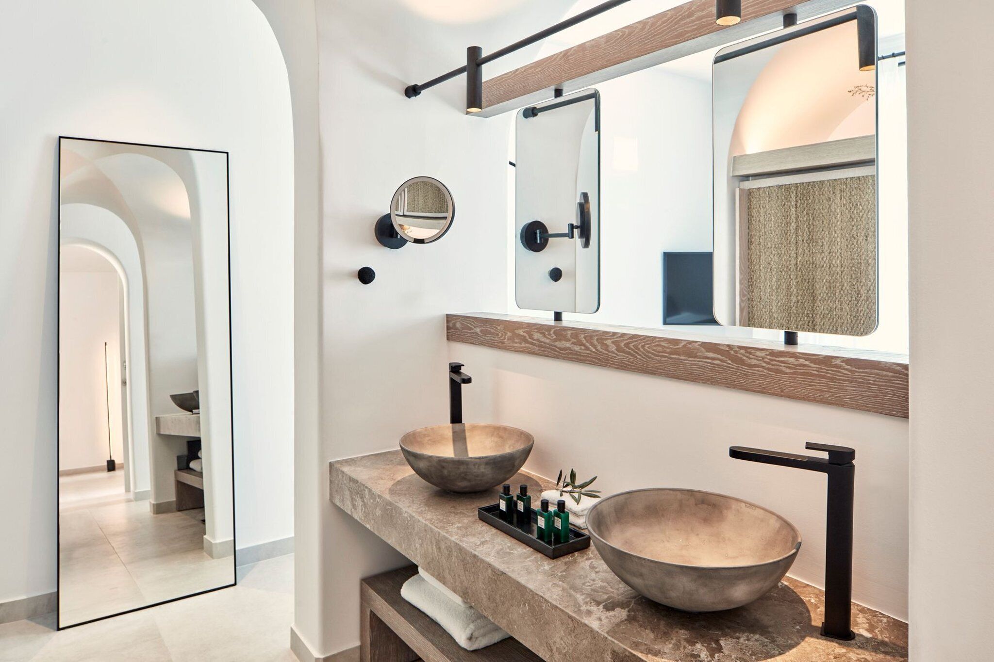 A modern bathroom with two large, round sinks, a mirror, and a wooden vanity.