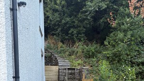 A narrow outdoor pathway leading to a wooden gate, surrounded by a gravel path and a wooden fence. - Tranquil Matlock Bath Retreat With 2 Bedrooms (Matlock)