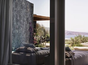 A modern outdoor seating area with a stone wall and a view of the sea. - Villa Elythiona, Divine Sea Views, Private Pool, Furnished Terrace, Sanrotini (Oia, Santorini)