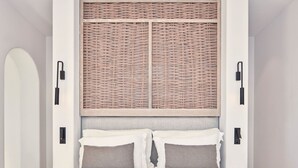 Quarto com cama, duas luminárias de apoio, cabeceira com painel trançado e luminária fixada na parede.