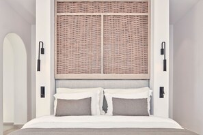 Ein Schlafzimmer mit einem Bett, zwei Nachttischlampen, einem Kopfteil mit einem Gewebepanel und einer wandmontierten Leuchte.