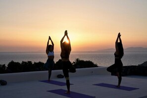 Three individuals practicing yoga on a rooftop with a sunset view. - Villa Orythion, Divine Sea Views, Private Pool, Furnished Terrace, Sanrotini (Oia, Santorini)