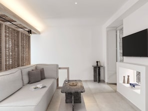 A modern living room with a sofa, a coffee table, and a flat-screen TV mounted on the wall. - Villa Orythion, Divine Sea Views, Private Pool, Furnished Terrace, Sanrotini (Oia, Santorini)