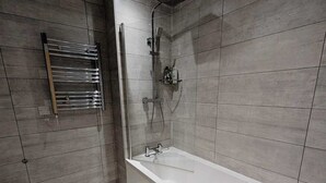 Une salle de bain moderne équipée d’une baignoire, d’une douche et d’un porte-serviettes.