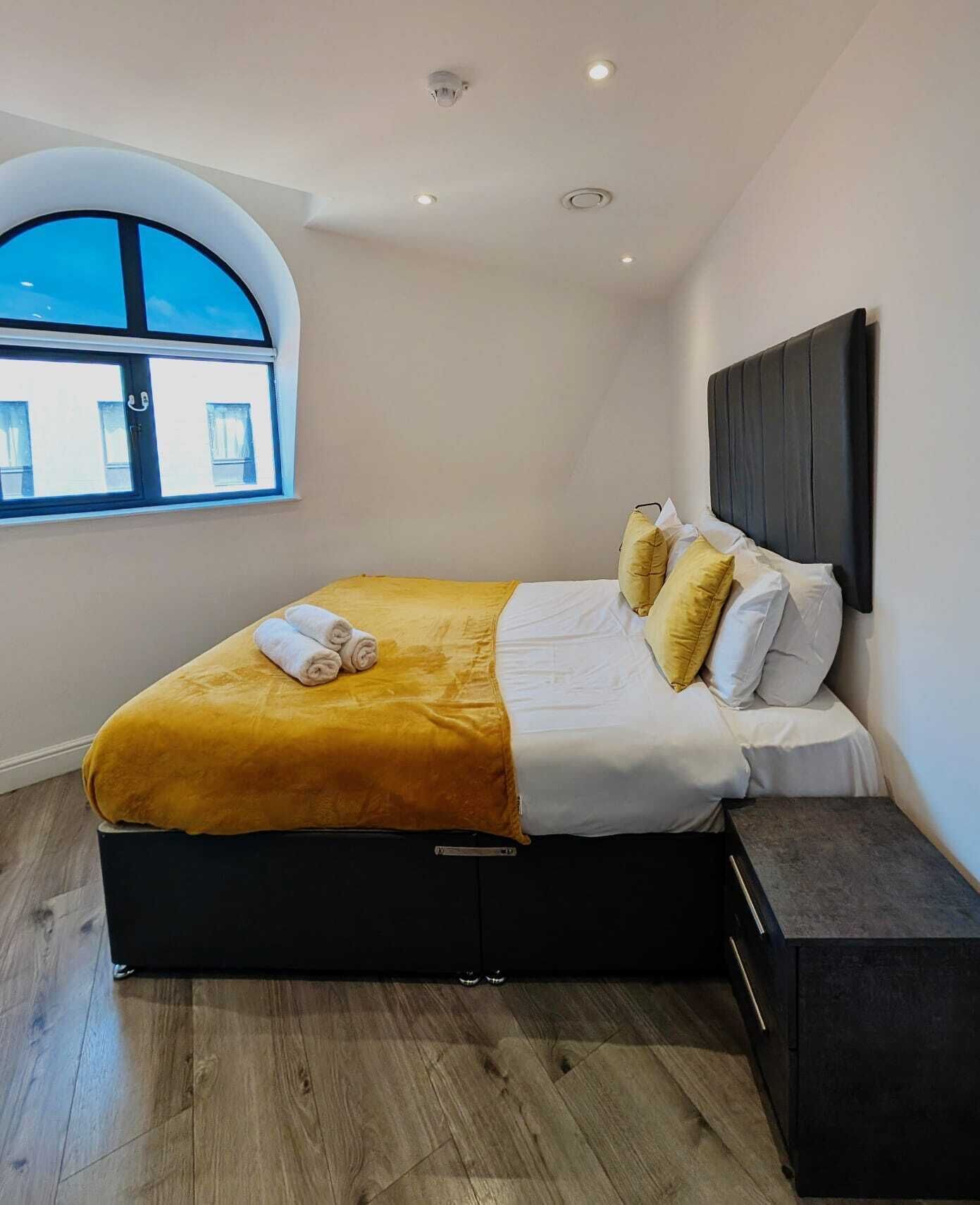 Une chambre moderne avec un grand lit, une fenêtre et une tête de lit intégrée.
