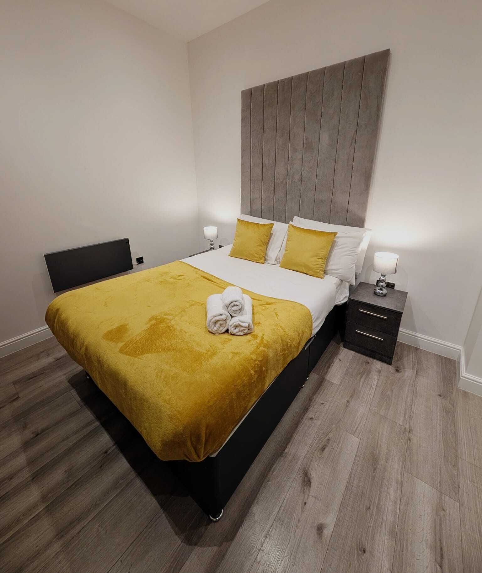 A modern bedroom with a bed, bedside tables, and a wooden floor.