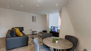 Un salon moderne comprenant un canapé, des fauteuils, une table basse et un téléviseur.