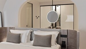 A modern hotel room with a large bed, a round mirror, and a built-in control panel. - Villa Solerion, Divine Sea Views, Private Pool, Furnished Terrace, Sanrotini (Oia, Santorini)