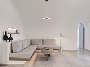 A modern living room with a sectional sofa, a coffee table, and a pendant light. - Villa Solerion, Divine Sea Views, Private Pool, Furnished Terrace, Sanrotini (Oia, Santorini)