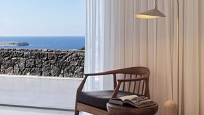 A room with a view of the sea, a chair with a book, and a floor lamp. - Villa Solerion, Divine Sea Views, Private Pool, Furnished Terrace, Sanrotini (Oia, Santorini)