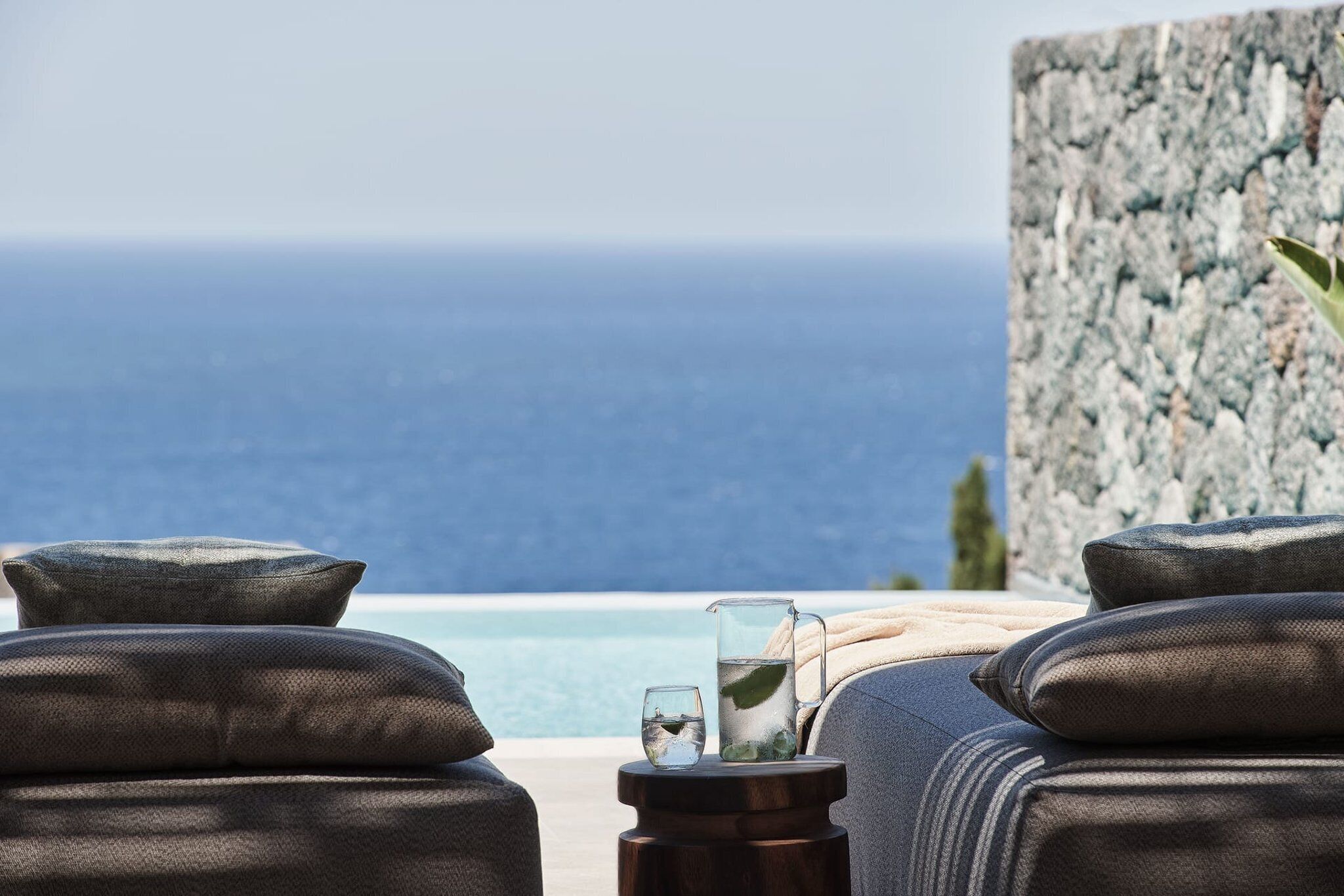 A seaside view with a stone wall, a clear sky, and a water body.