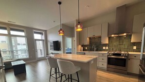 A modern kitchen with a central island, bar stools, a built-in oven, and pendant lighting. - Modern 1BR Bridge Park in Dublin with Balcony and Pool (Dublin)