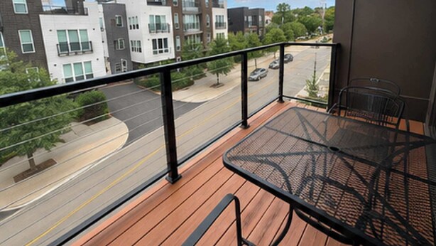 A balcony with a table and chairs, overlooking a street with modern buildings and a clear sky. - Modern 1BR Bridge Park in Dublin with Balcony and Pool (Dublin)