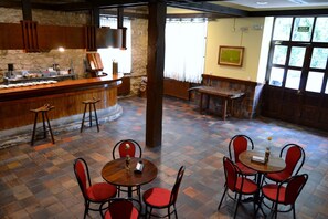 Un interior de restaurante con barra, varias mesas y sillas.