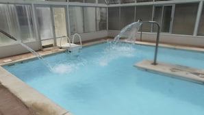 Una piscina con agua cristalina, un trampolín y una fuente.