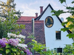 A white building with a red-tiled roof, a chimney, and a circular window. - Apartment 'In den Bäumen' – Quiet Apartment on the Edge of the Forest near Freiburg (Bollschweil)