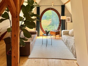 Ein gemütliches Zimmer mit einem großen Rundfenster, einer Couch, einem kleinen Tisch und einem Blumentopf.