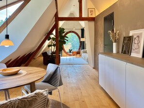 A modern interior with a dining area, kitchen, and a large window with a view. - Apartment 'In den Bäumen' – Quiet Apartment on the Edge of the Forest near Freiburg (Bollschweil)